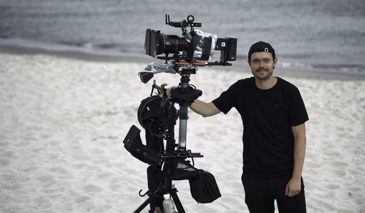 Kameramann Micky Graeter mit einer Kamera und Steadicam an einem Strand